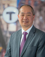 Phillip Eng in a dark gray suit in front of a light gray background