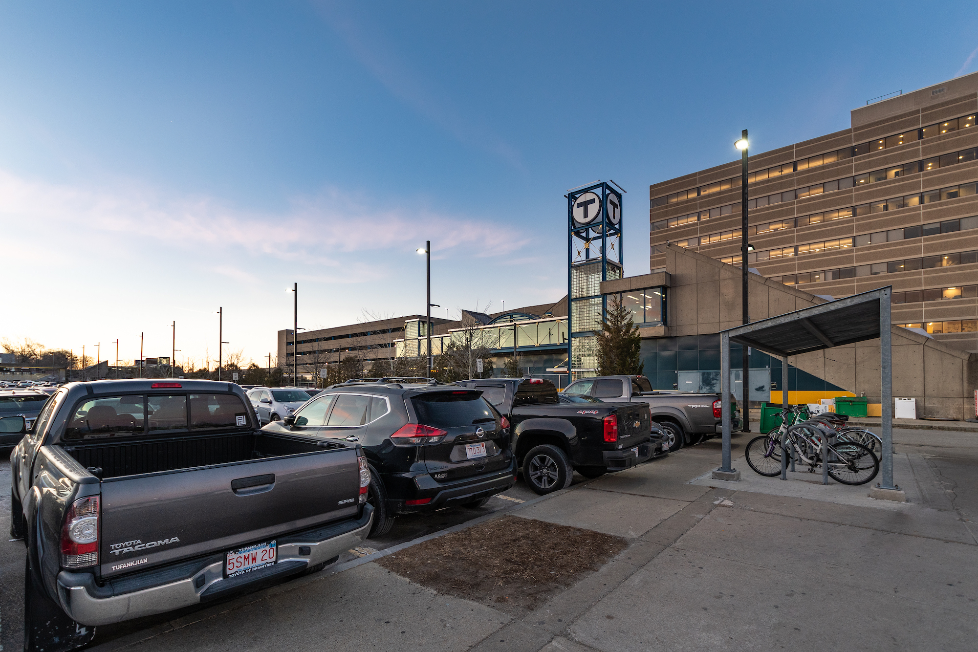 North Quincy Station: T sign, parking lot with cars, bike racks