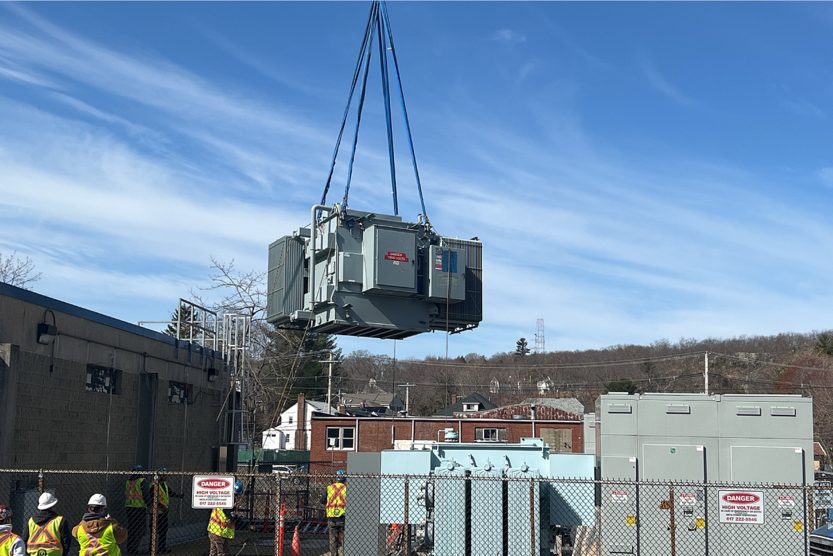 Crane delivering a large piece of equipment to a rail yard