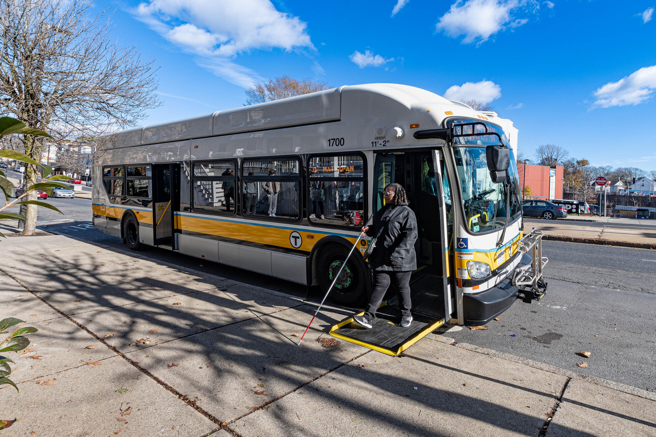 vision-impaired rider exiting a bus using a walking aid 