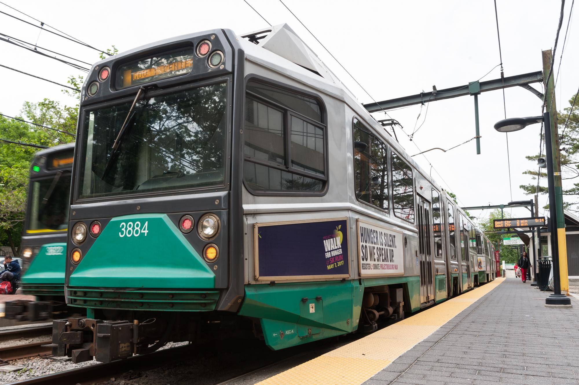 A Green Line train arrives at an above-ground platform.